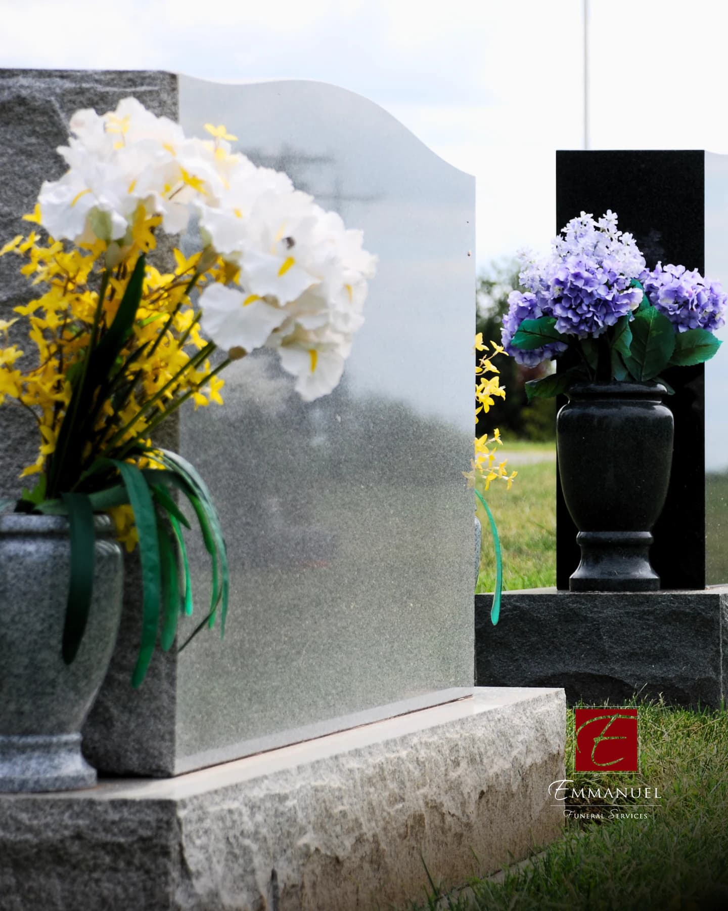 A granite headstone dressed with flowers at a graveside