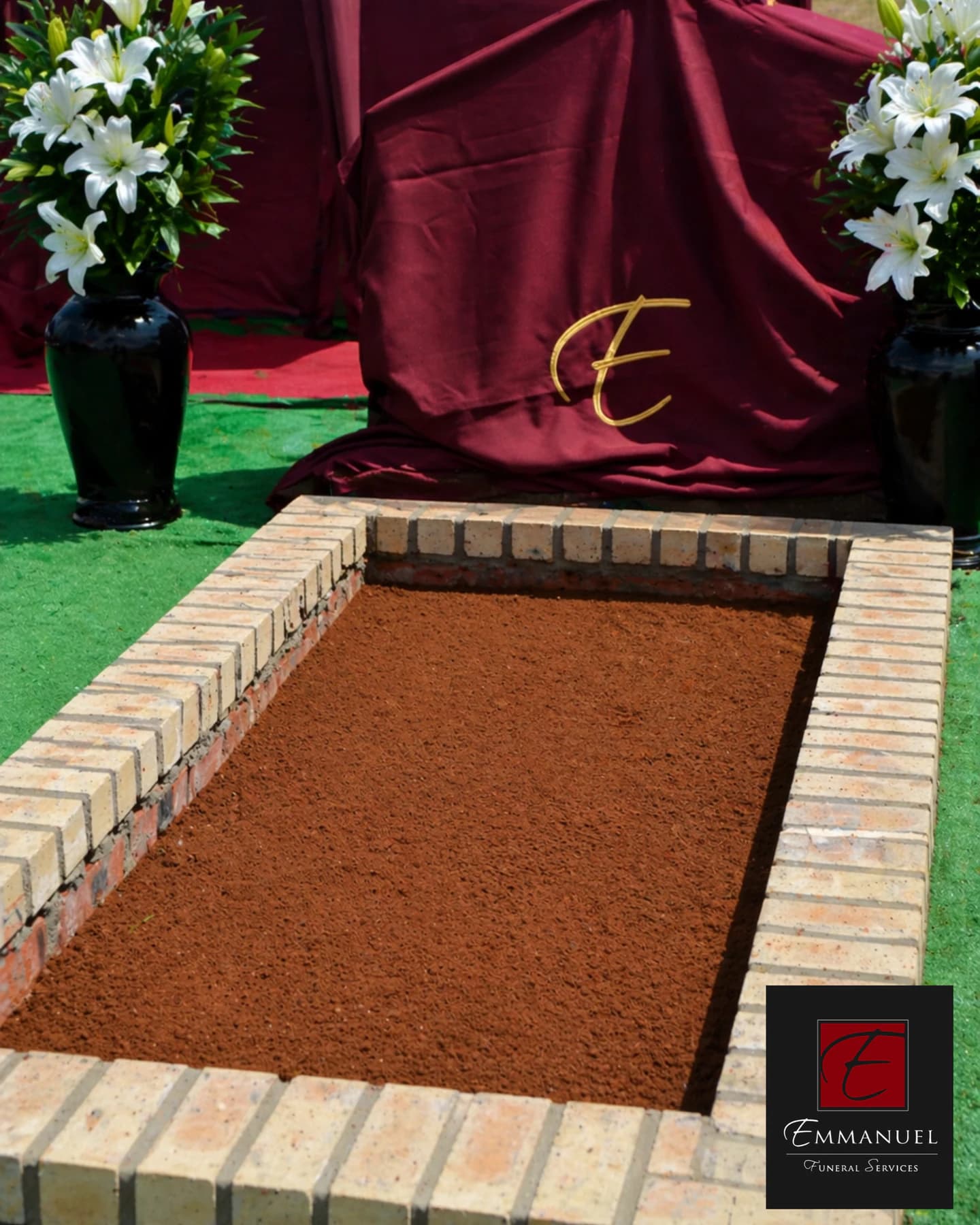 A prepared graveside with a brick surround and an Emmanuel Funeral Services drape