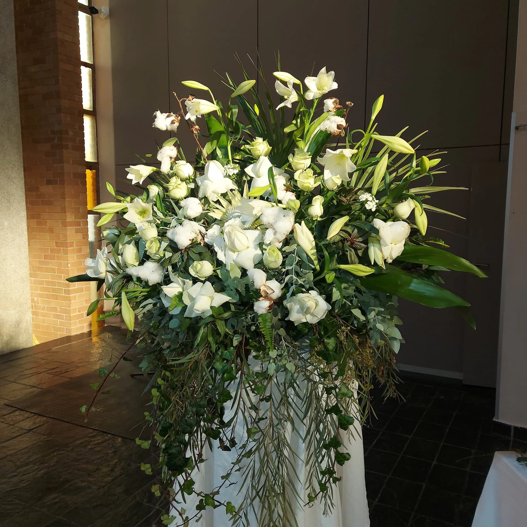 A tall white and green floral spray on a pedestal